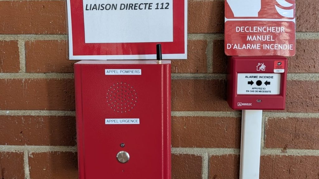 Borne d'appel d'urgence GSM 4G rouge « Appel pompiers » installée à côté du déclencheur manuel d'alarme incendie dans un bâtiment communal de Fonsorbes (31)